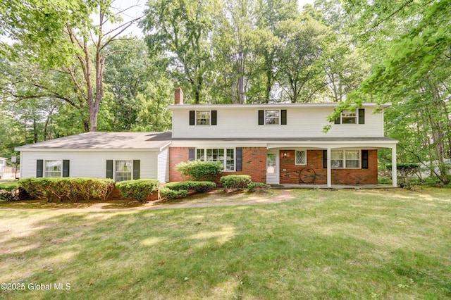 15 Garrison Ln, Clifton Park, NY 12019 - view of front facade featuring a chimney, a front lawn, brick siding, and view of wooded area