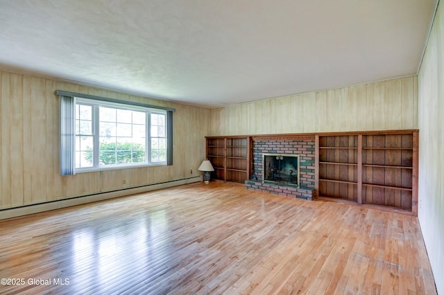 15 Garrison Ln, Clifton Park, NY 12019 - unfurnished living room featuring wood finished floors, a baseboard radiator, a brick fireplace, and wood walls
