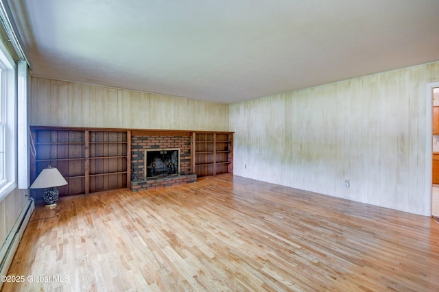 15 Garrison Ln, Clifton Park, NY 12019 - unfurnished living room featuring baseboard heating, wood finished floors, wood walls, and a brick fireplace