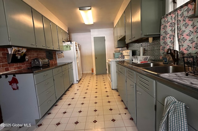 kitchen with a sink, decorative backsplash, dark countertops, and white appliances