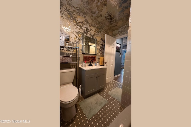 bathroom with vanity, toilet, and wallpapered walls