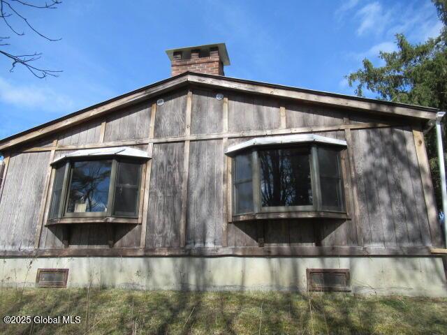 view of side of property with crawl space and a chimney