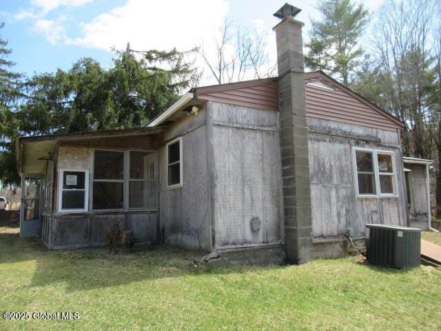 view of property exterior featuring a yard, a chimney, and central air condition unit