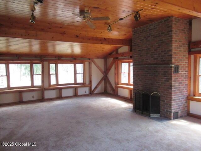 unfurnished living room with track lighting, carpet flooring, wood ceiling, and ceiling fan