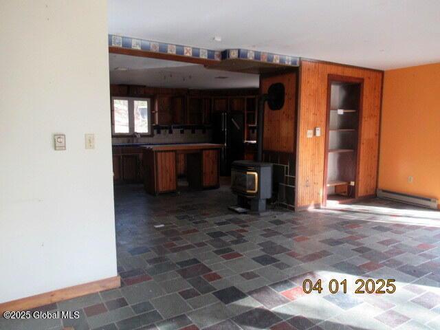 545 Stage Rd, Cambridge, NY 12028 - kitchen with freestanding refrigerator, wooden walls, a baseboard heating unit, and a wood stove