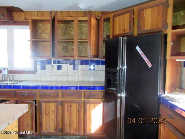 545 Stage Rd, Cambridge, NY 12028 - kitchen featuring tile counters, a sink, brown cabinetry, and black fridge