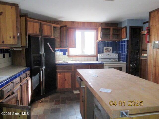 545 Stage Rd, Cambridge, NY 12028 - kitchen featuring black refrigerator with ice dispenser, tasteful backsplash, white electric range oven, and brown cabinetry