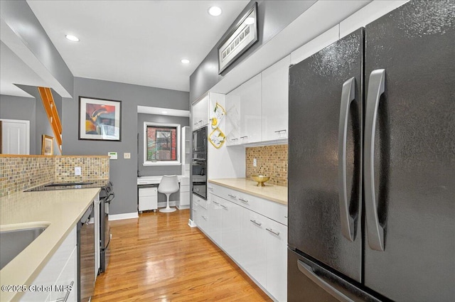 101 E Krumkill Rd, Albany, NY 12208 - kitchen with freestanding refrigerator, light wood-style floors, backsplash, white cabinets, and black microwave