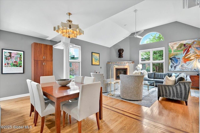 101 E Krumkill Rd, Albany, NY 12208 - dining area featuring light wood finished floors, a glass covered fireplace, vaulted ceiling, ceiling fan, and ornate columns