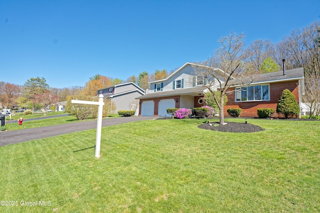traditional-style house with an attached garage, driveway, a front lawn, and brick siding