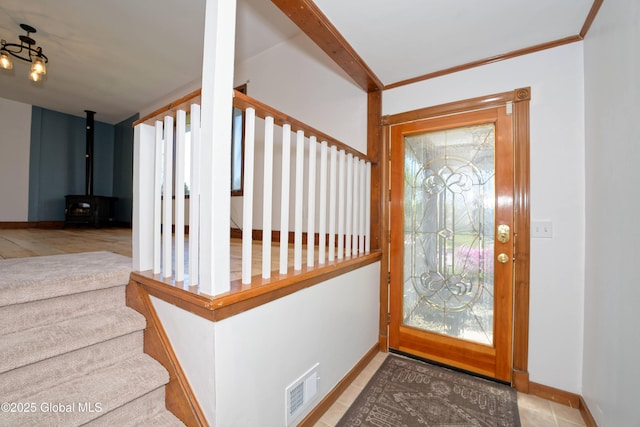 tiled entrance foyer featuring visible vents, a wood stove, baseboards, and stairway