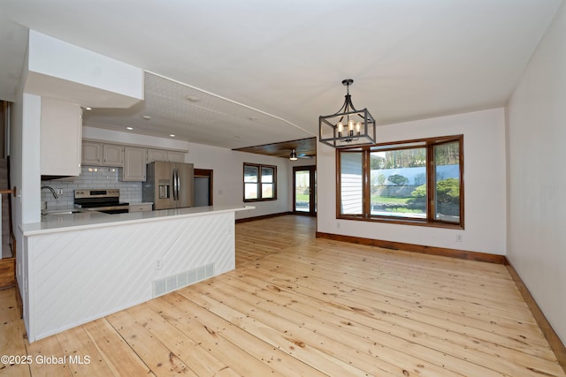 kitchen with appliances with stainless steel finishes, baseboards, a peninsula, and visible vents