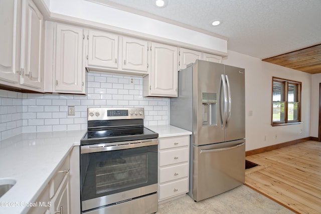 kitchen featuring light countertops, appliances with stainless steel finishes, baseboards, and decorative backsplash