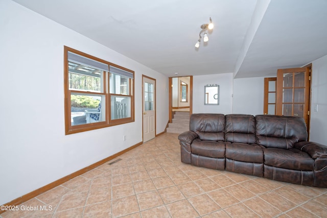living room featuring stairs, baseboards, visible vents, and light tile patterned floors