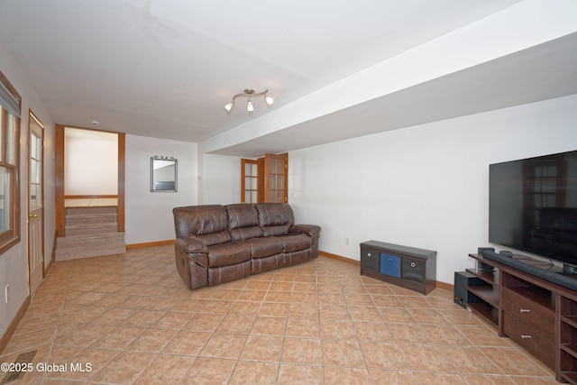 living area featuring baseboards and stairs