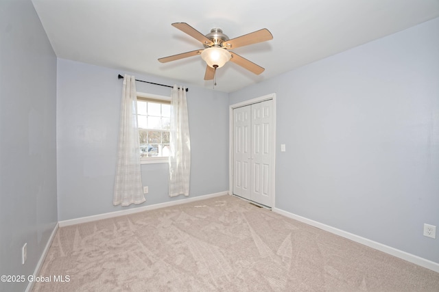 carpeted empty room featuring baseboards and ceiling fan