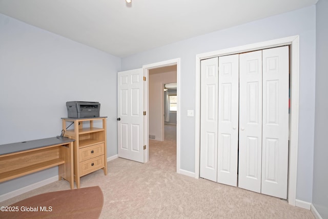 bedroom with light colored carpet, baseboards, and a closet