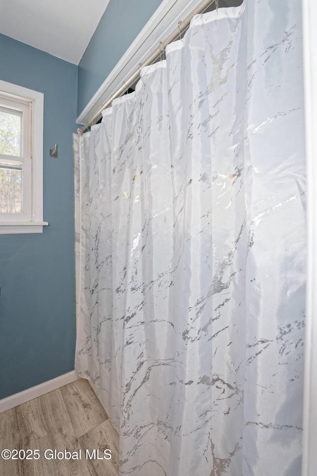 bathroom with baseboards, wood finished floors, and curtained shower