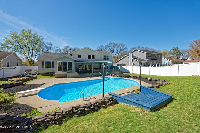 view of swimming pool with a diving board, a fenced in pool, a fenced backyard, a lawn, and a patio