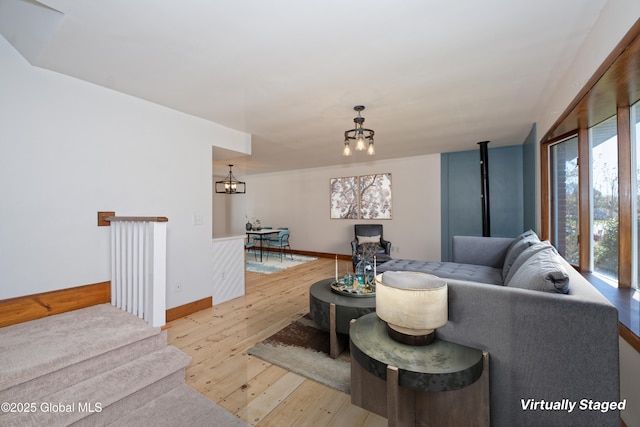 living area with an inviting chandelier, baseboards, and light wood-style floors