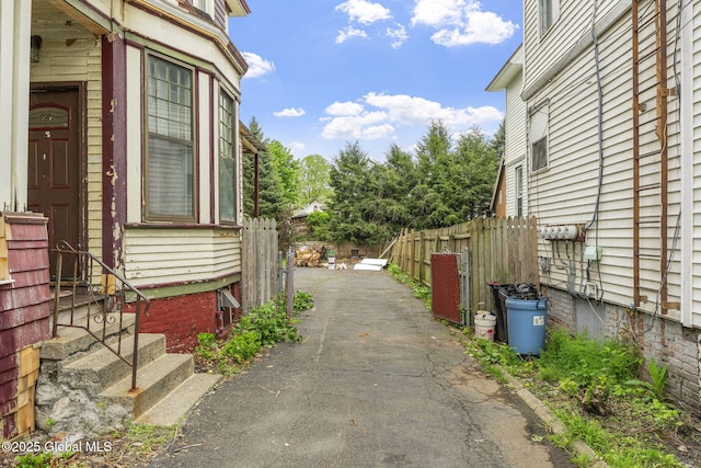 view of side of home featuring fence, entry steps, and driveway