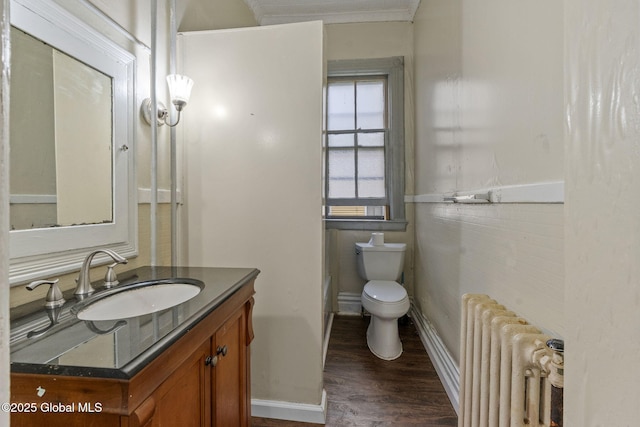 bathroom featuring radiator, wood finished floors, toilet, vanity, and crown molding
