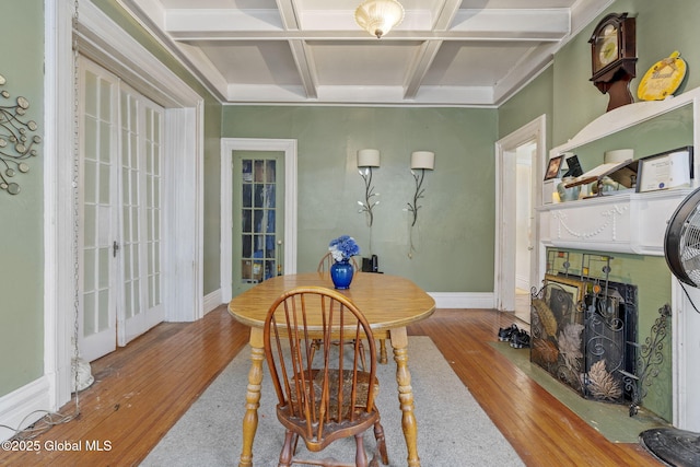 dining area featuring coffered ceiling, wood-type flooring, beamed ceiling, and baseboards