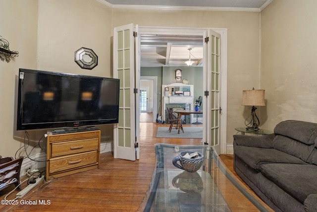 living area featuring wood finished floors, french doors, ornamental molding, and baseboards