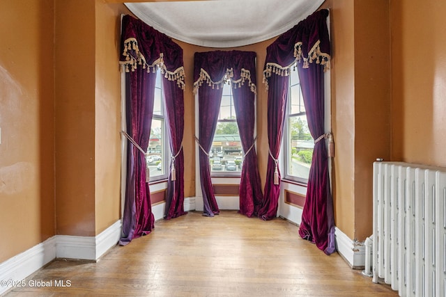 spare room featuring radiator, wood finished floors, and baseboards