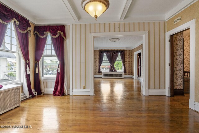 foyer with wallpapered walls, radiator heating unit, wood finished floors, beam ceiling, and baseboards