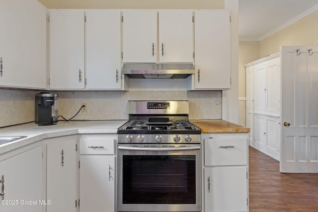 kitchen with under cabinet range hood, gas range, crown molding, light countertops, and white cabinetry