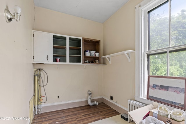 laundry room with dark wood-style floors, plenty of natural light, radiator heating unit, and baseboards