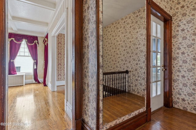 hallway with hardwood / wood-style floors, wallpapered walls, radiator, and baseboards