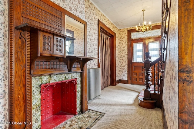 carpeted foyer featuring wallpapered walls, a chandelier, and ornamental molding