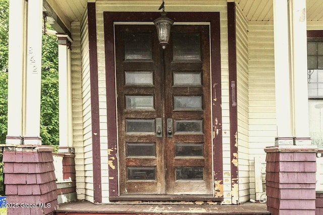 property entrance with covered porch and french doors