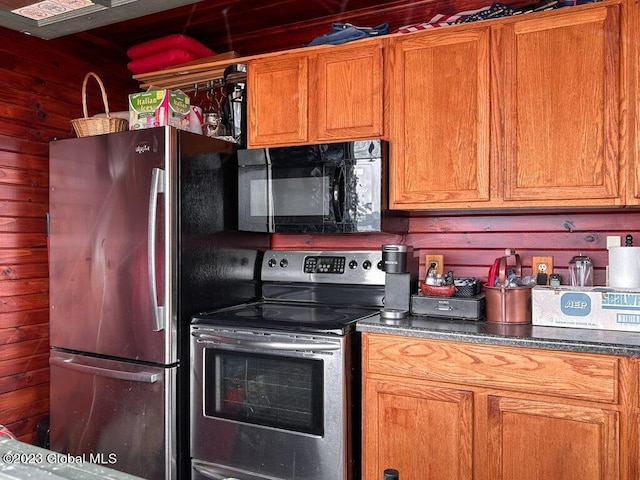 9667 Lake Shore Dr, Hague, NY 12836 - kitchen with stainless steel appliances, wooden walls, brown cabinets, and dark countertops