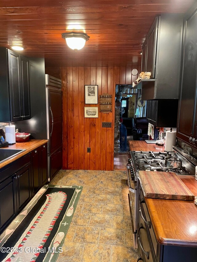 9667 Lake Shore Dr, Hague, NY 12836 - kitchen with butcher block countertops, stone finish flooring, wood ceiling, gas range oven, and wood walls
