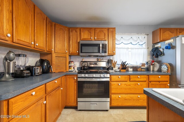 275 Nelson Ave, Saratoga Springs, NY 12866 - kitchen with dark countertops, brown cabinetry, and appliances with stainless steel finishes