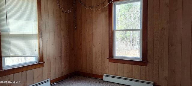 empty room with wooden walls, carpet, a baseboard heating unit, and baseboard heating