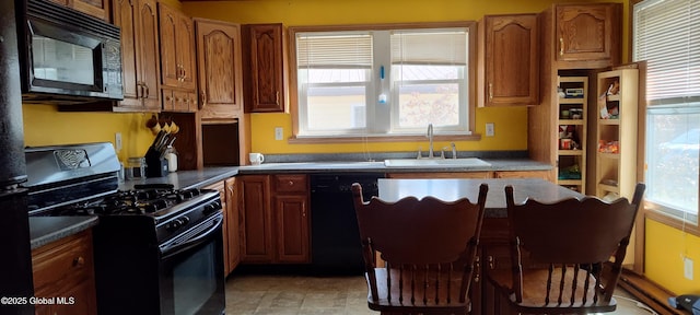 kitchen with dark countertops, a sink, black appliances, and plenty of natural light