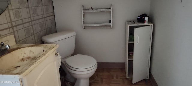 bathroom with vanity, tile walls, baseboards, and toilet