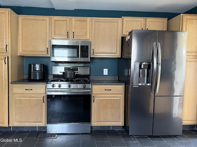 294 Main St, Hudson Falls, NY 12839 - kitchen featuring appliances with stainless steel finishes, dark countertops, light brown cabinetry, and dark tile patterned floors