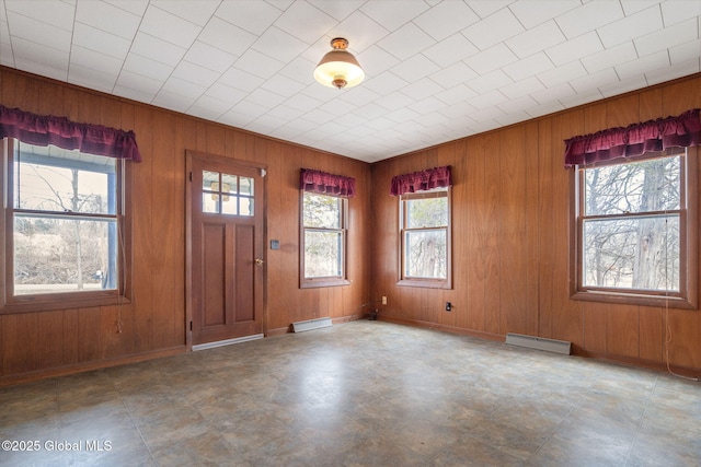 foyer with baseboards, wood walls, and baseboard heating
