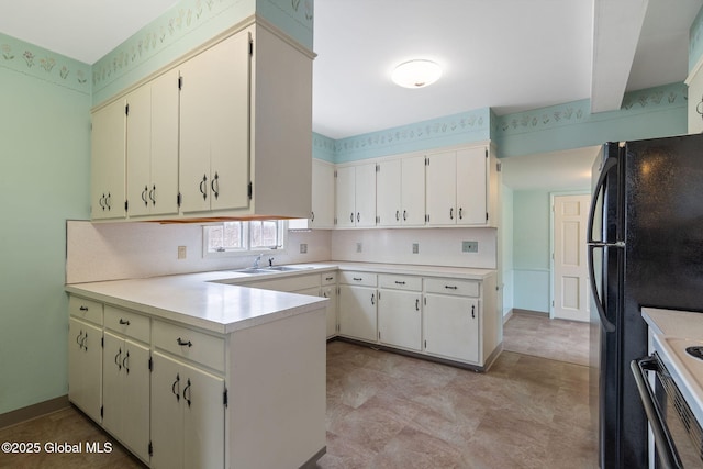 kitchen featuring baseboards, light countertops, a sink, and a peninsula