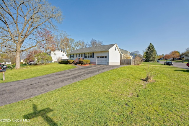 view of front facade featuring fence, an attached garage, a front yard, and aphalt driveway