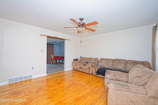 living room with baseboards, ceiling fan, light wood-style flooring, and visible vents