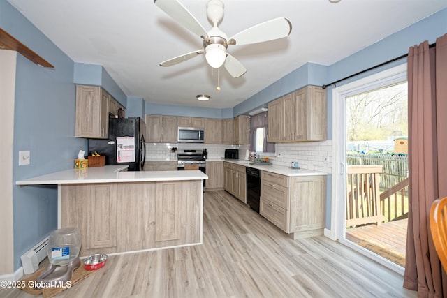 kitchen with light countertops, a sink, black appliances, and tasteful backsplash