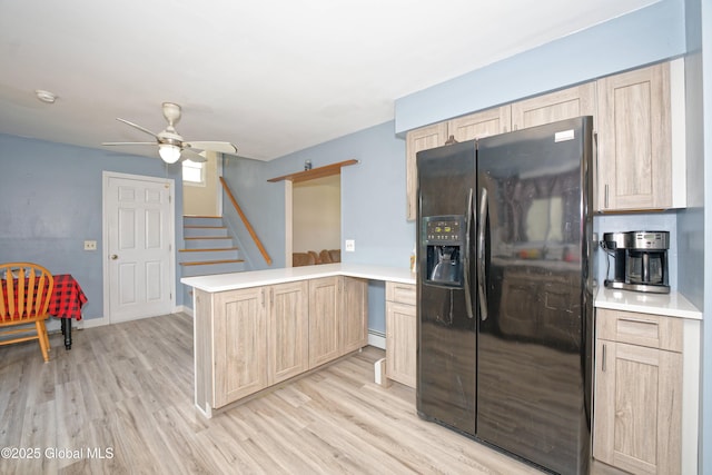 kitchen with a ceiling fan, a peninsula, light wood finished floors, light brown cabinets, and black fridge