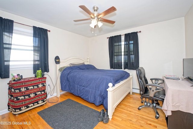 bedroom featuring a baseboard radiator, a ceiling fan, and wood finished floors