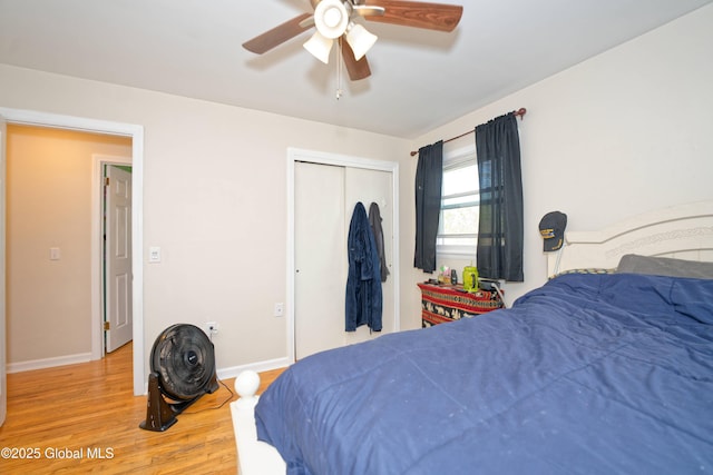 bedroom with baseboards, a ceiling fan, wood finished floors, and a closet